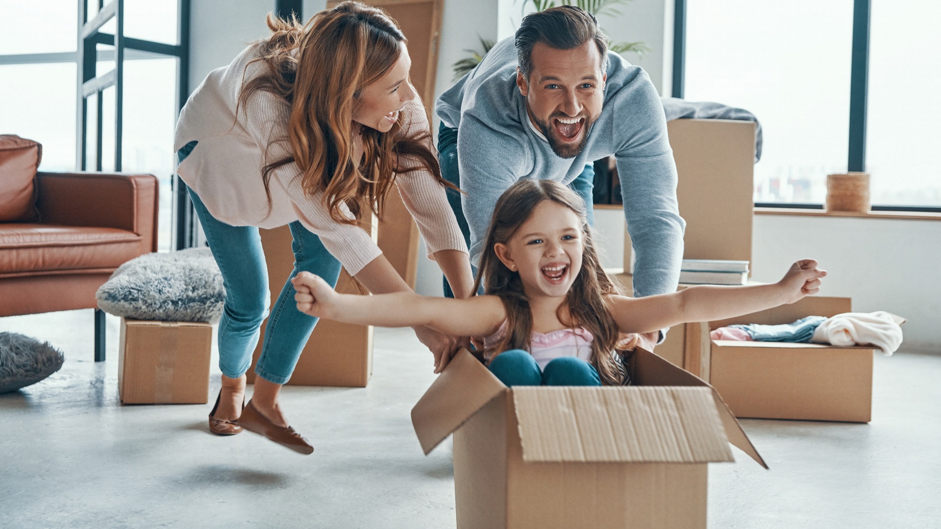 Die Familie lächelt und packt ihre Sachen aus, während sie in eine neue Wohnung umzieht